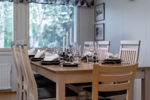 A dining table set with plates, glasses, and candles, surrounded by chairs. - Santa's Star Residence - Grand Apartment (Rovaniemi)