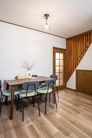 A dining area with a wooden table and chairs, a ceiling light fixture, and a wooden staircase. - U-neighbor Noda (Osaka, Fukushima-ku)