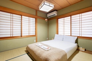 A traditional Japanese-style room with tatami flooring, a bed with white bedding, and shoji screens. - U-neighbor Noda (Osaka, Fukushima-ku)