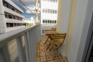 Un balcon avec une table et des chaises en bois, un sol carrelé et une balustrade.