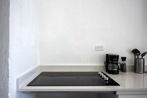 A kitchen with a black induction cooktop, a coffee maker, and a spice rack. - Nando's Place 4 - Charming 1BR Apt near Old San Juan and Beach (San Juan)
