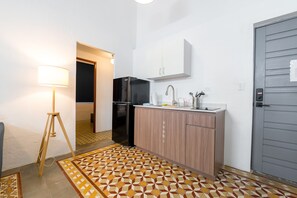 A compact kitchen with a refrigerator, sink, and cabinet, a patterned floor, and a lamp. - Nando's Place 2 - Charming 2BR Apt near Old San Juan and Beach (San Juan)