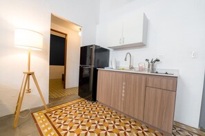 A compact kitchen with a refrigerator, a sink, and a cabinet. There's a patterned rug on the floor and a lamp on a tripod stand. - Nando's Place 5 - Charming 2BR Apt near Old San Juan and Beach (San Juan)