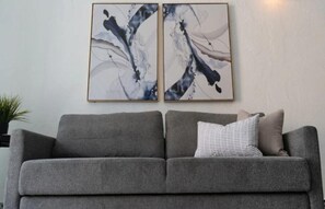 A grey sofa with a striped pillow against a wall with two abstract paintings. - Elokut Loft 4 - Steps from Old San Juan and Escambron Beach (San Juan)