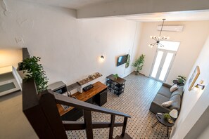 A modern living space with a staircase, a dining area with a wooden table, a sofa, and a kitchen area with a microwave. - Elokut Loft 4 - Steps from Old San Juan and Escambron Beach (San Juan)