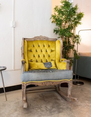 A vintage-style armchair with a tufted backrest and a single yellow cushion. - Juliette Hostel, Bed in 8-Bed Female Dorm, Old San Juan (San Juan)