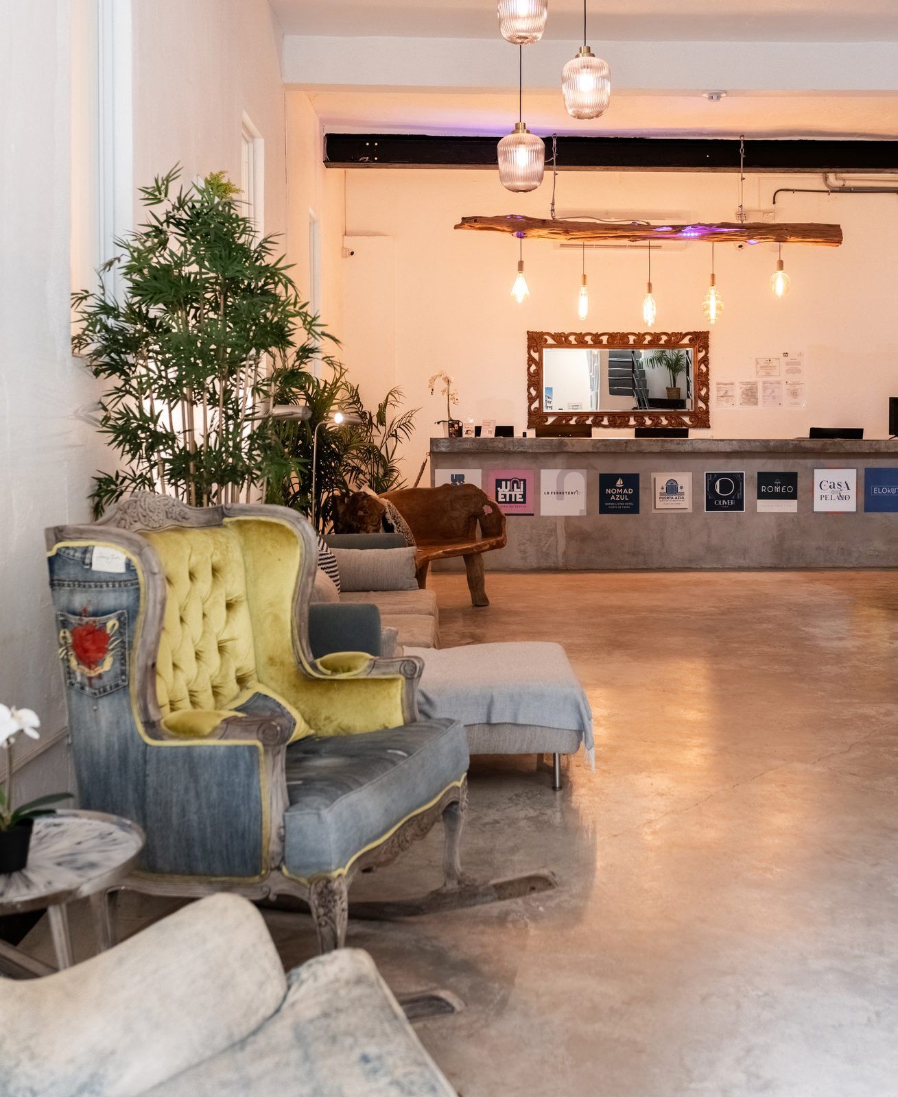 A reception area with a wooden reception desk, a large mirror, and a seating area with a sofa and armchairs.