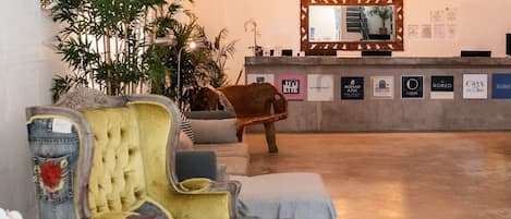 A reception area with a wooden reception desk, a large mirror, and a seating area with a sofa and armchairs.