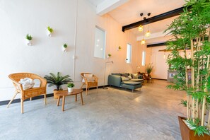 Un saló modern amb un sofà, cadires, una taula petita i plantes en testos.