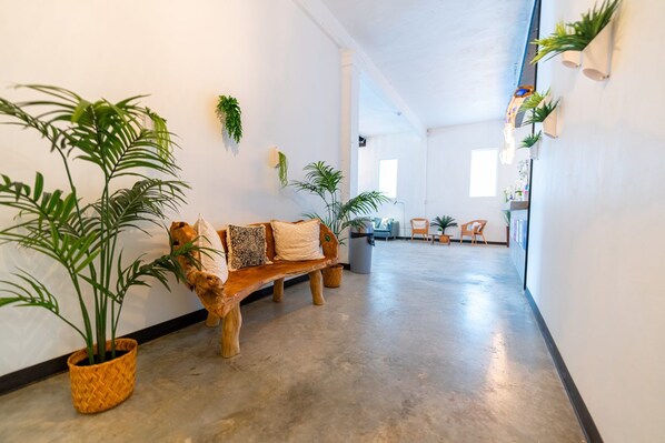 Un passadís ampli amb una banca de fusta, plantes en testos i una vista a una altra habitació.