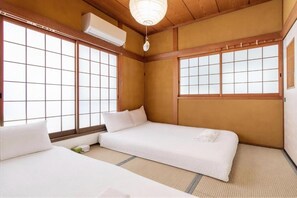 A traditional Japanese-style room with tatami flooring, a futon bed, and sliding shoji doors. - U-neighbor Denpo (Osaka, Konohana-ku)