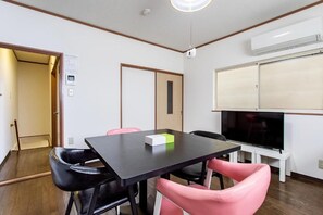 A room with a black table, two chairs, a television, and a door. - U-neighbor Denpo (Osaka, Konohana-ku)
