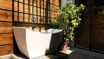 Una bañera blanca de diseño moderno, ubicada frente a una pared de madera con una ventana.