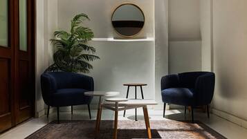 A room with two dark blue armchairs, a small round table, and a large mirror on the wall.