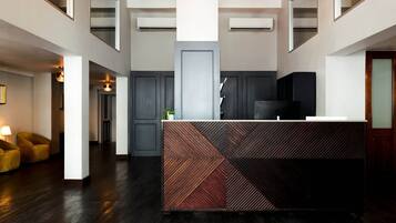 Un espace d’accueil moderne avec un comptoir aux motifs géométriques, un revêtement de sol en bois foncé et un design minimaliste.
