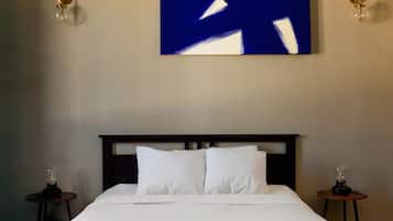 Una habitación de hotel con una cama grande, dos mesitas de noche y un cuadro abstracto colgado en la pared.