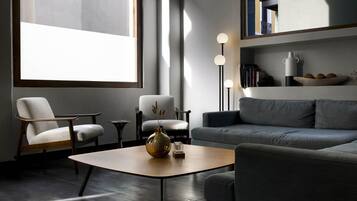 Una sala de estar moderna con un sofá, dos sillones, una mesa de centro y una lámpara de pie.