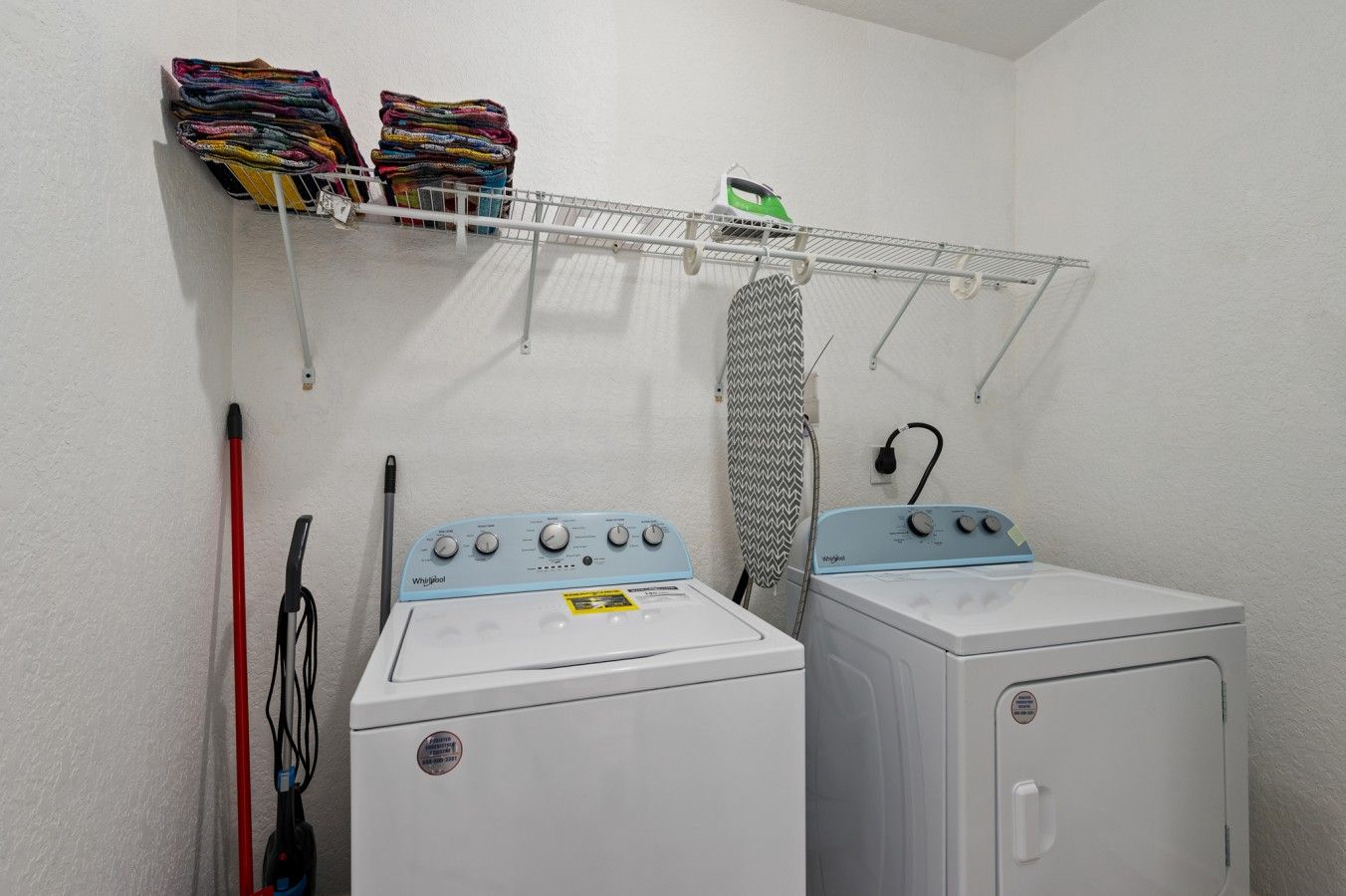 Un espacio para lavandería con dos lavadoras, un tendedero y un planchado colgante.