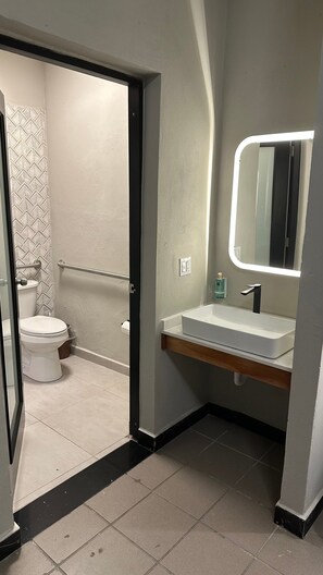 Un bany amb un vàter blanc, un lavabo amb mirall i un escurapobrins.