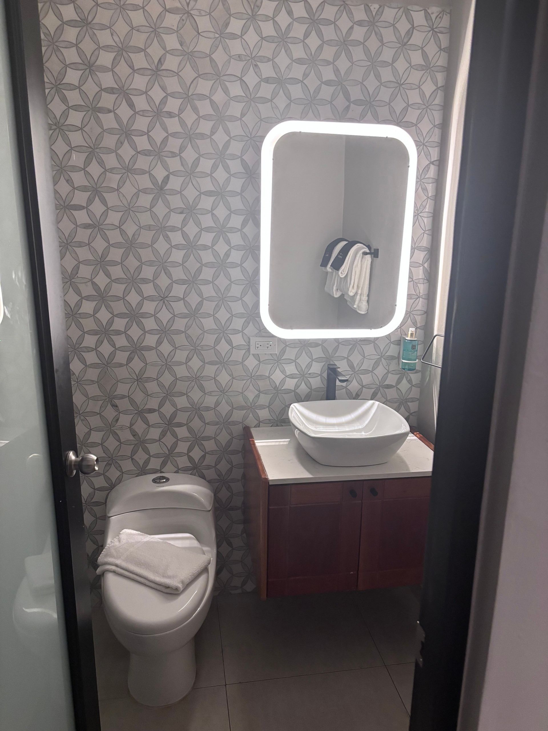 A bathroom with a toilet, a sink, a mirror, and a towel rack.