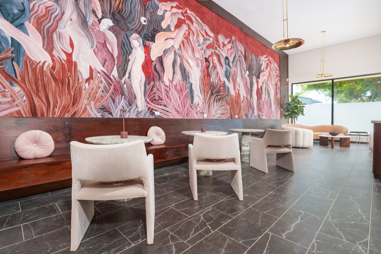 A modern interior with a large abstract mural, seating areas, and a view through a large window.