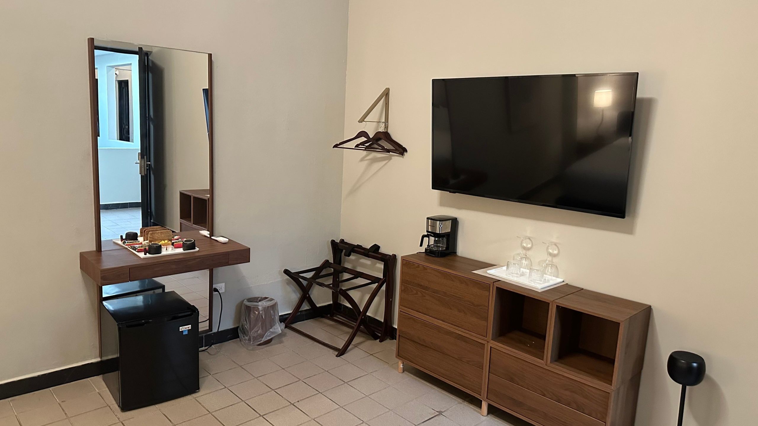 Una habitación de hotel con cama, escritorio con silla, televisor, cafetera y armario.