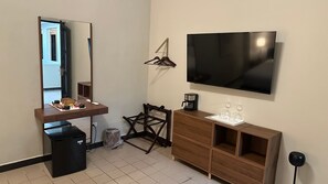 A hotel room with a bed, a desk with a chair, a TV, a coffee maker, and a wardrobe. - The Oliver, Deluxe Room with King Bed, Old San Juan (San Juan)