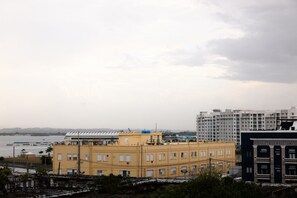 A coastal cityscape with a prominent yellow building, a modern structure with a curved roof, and a hotel named 'HOTEL PUERTO VALD'. - The Oliver, Deluxe Room with King Bed, Old San Juan (San Juan)