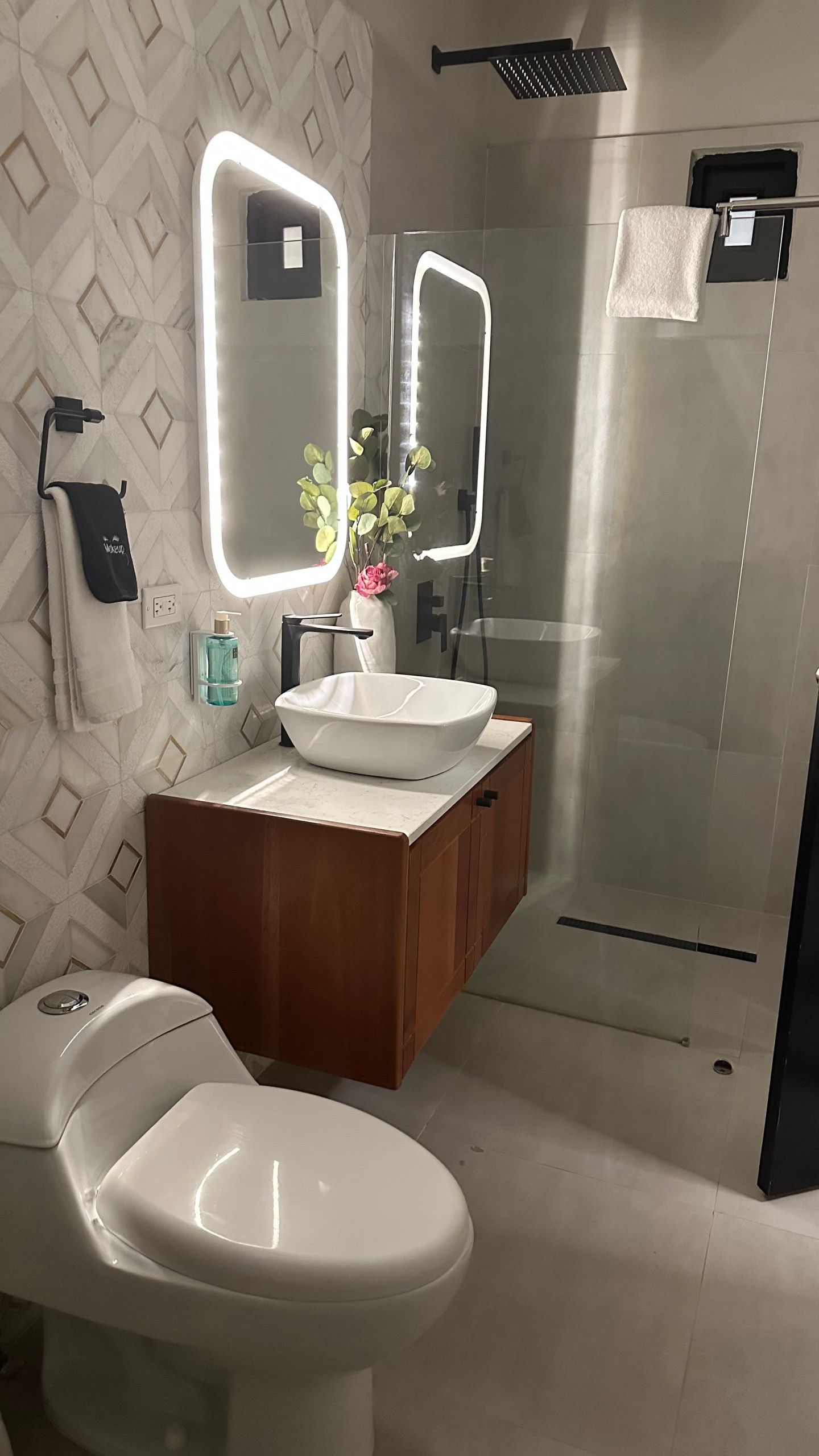 A modern bathroom with a toilet, sink, and mirrors.