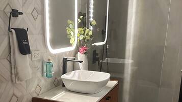 A modern bathroom with a toilet, sink, and mirrors.