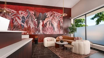 Un vestíbulo moderno con mostrador de recepción, un gran mural abstracto, área de estar con sofás y un amplio ventanal con vistas a zonas verdes.