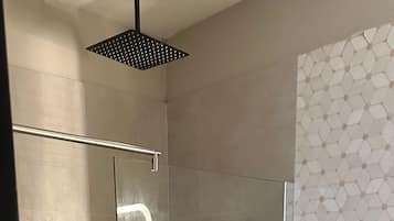 Un baño moderno con ducha de vidrio, inodoro y toallero.