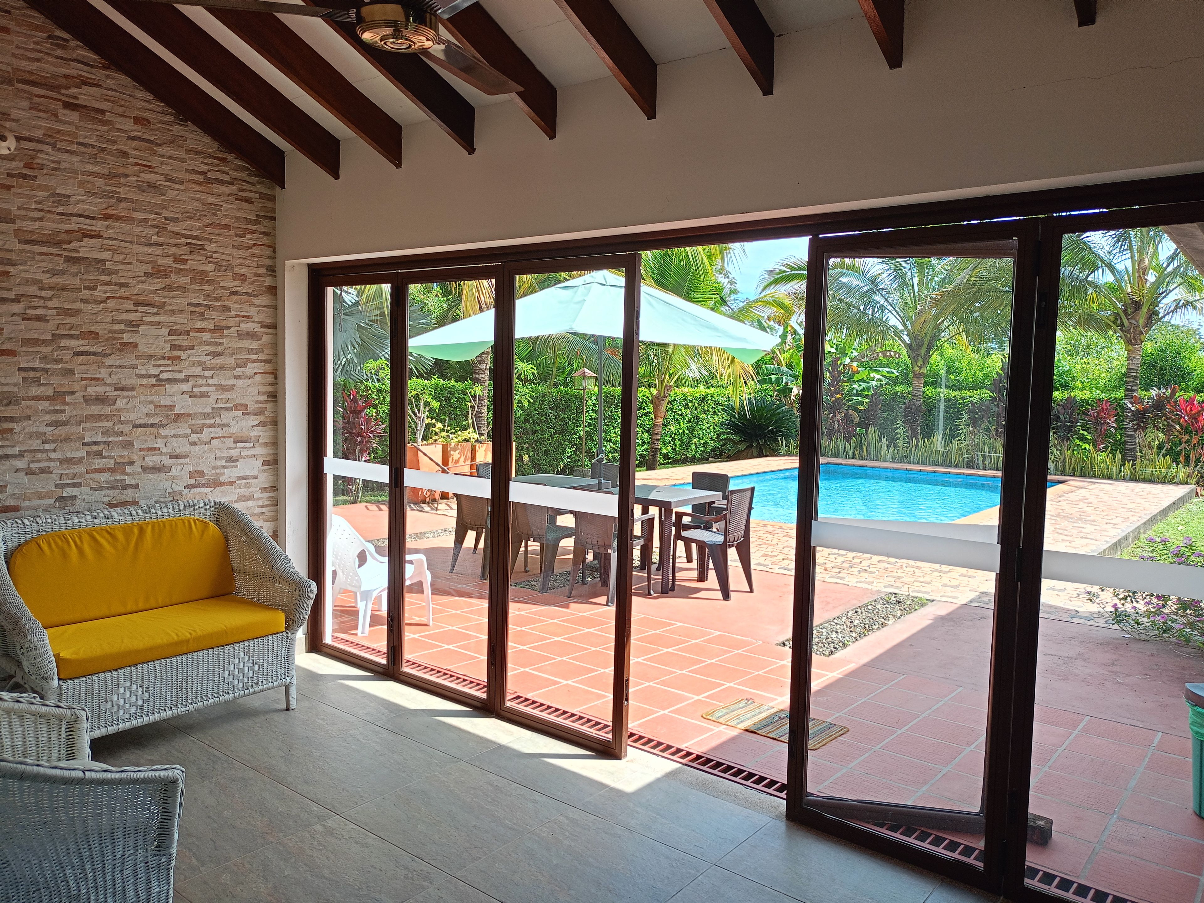 A room with a view of a swimming pool, a dining area with outdoor furniture, and a large sliding glass door.