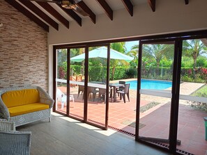 A room with a view of a swimming pool, a dining area with outdoor furniture, and a large sliding glass door. - New Listing (Meta)