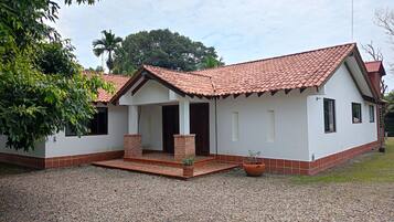 A single-story house with a tiled roof, a front porch, and a gravel driveway.