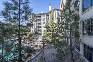 Un immeuble à plusieurs étages doté de balcons, entouré d’arbres et bordé d’une zone recouverte de gravier.