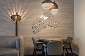 A modern dining area with a round table and four chairs, a wall-mounted light fixture, and a textured wall. - 1+Den @ Monache w/ Luxury Amenities; Dog Friendly! (Mammoth Lakes)