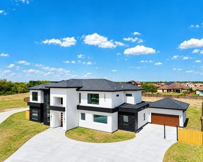 Ein modernes, zweistöckiges Haus mit Garage, Auffahrt und gepflegtem Rasen.