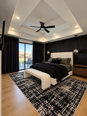 Ein modernes Schlafzimmer mit einem großen Bett, einem Deckenventilator und Blick ins Freie.