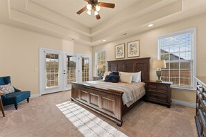 A bedroom with a large bed, a nightstand, a chair, and a ceiling fan. - Ledgestone Country Club Retreat (Branson)