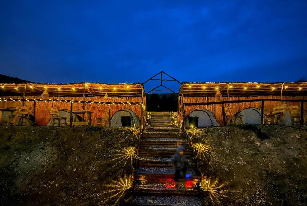 A building with a staircase leading to a covered entrance, surrounded by walls adorned with string lights.