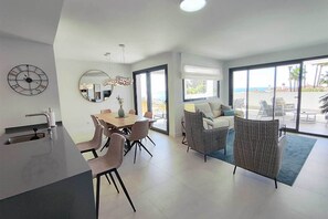 A modern living room with a dining area, large windows, and a view of the outdoors. - Apartment 'Pure South' with Mediterranean Views (San Luis De Sabinillas)