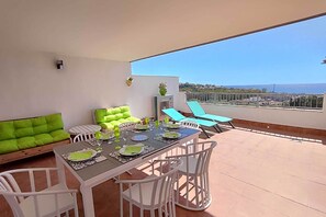 Ein Balkon mit Esstisch für vier Personen, einer Couch und zwei Loungestühlen.
