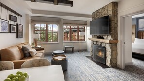 A living room with a stone fireplace, a flat-screen TV mounted above it, a sofa, and a dining table with apples on it. - Heavenly! South Lake Tahoe for Thanksgiving weekend and beyond. (South Lake Tahoe)