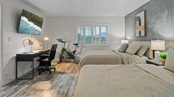 A bedroom with a desk, bicycle, and two beds.