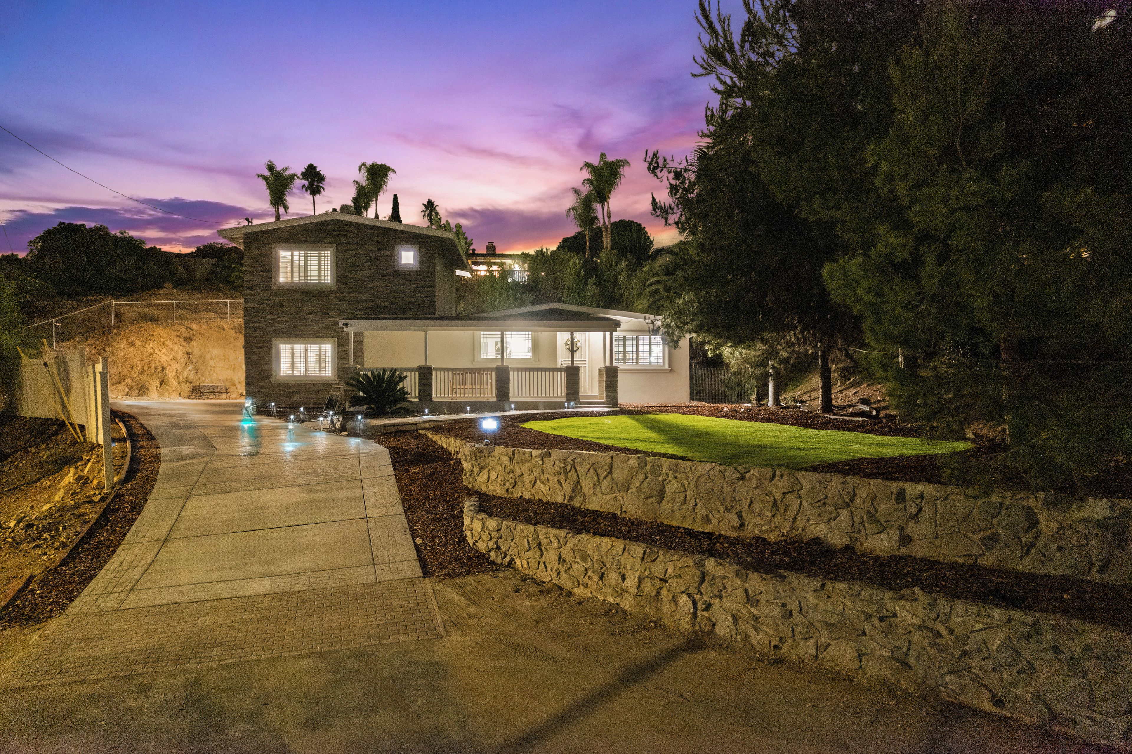A modern two-story house with a stone facade, a well-maintained lawn, and a driveway leading to the entrance.