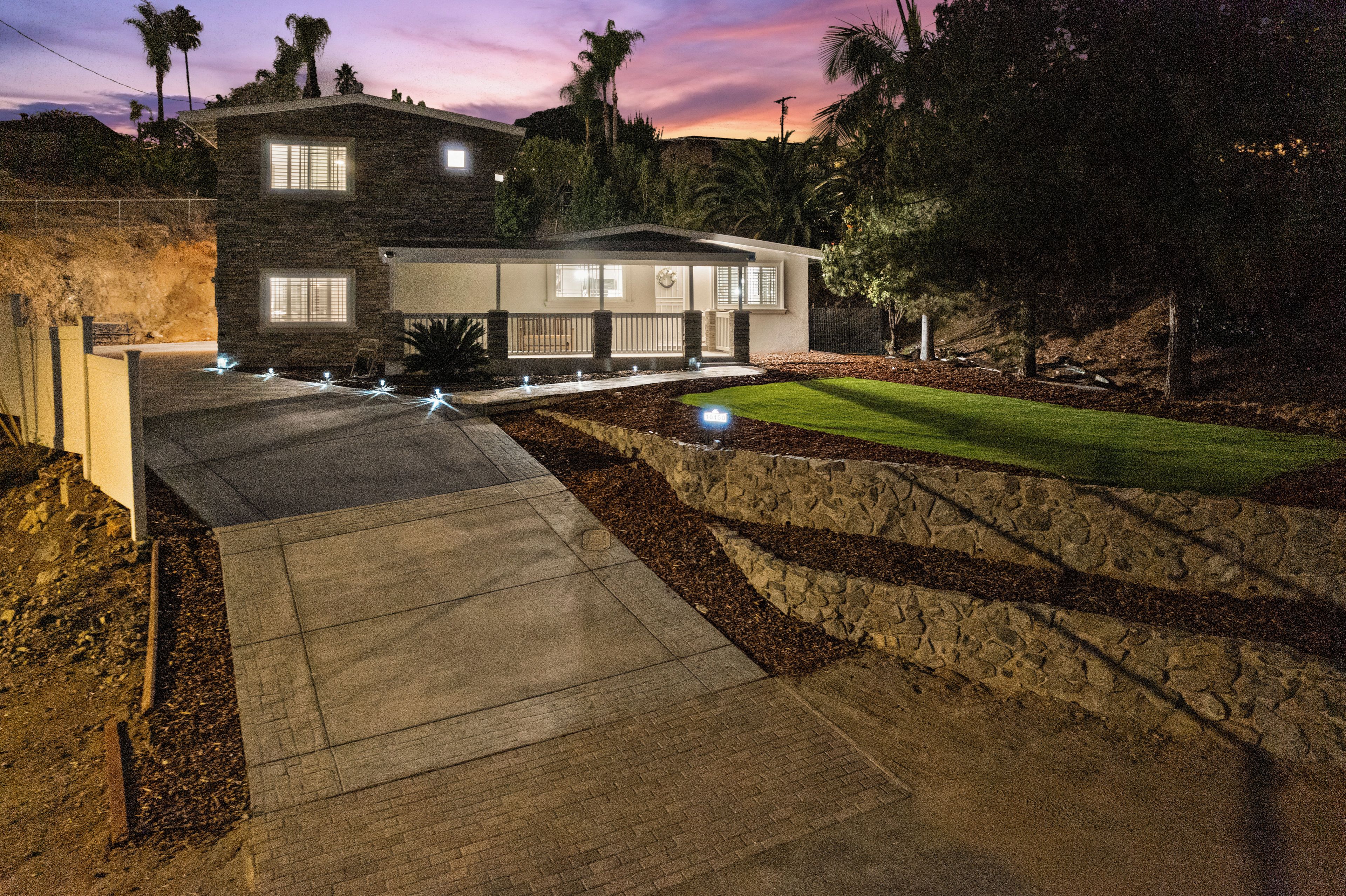 A modern two-story house with a stone facade, a well-maintained lawn, and a paved driveway.