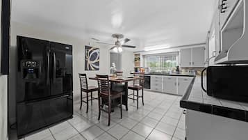 A modern kitchen with a black refrigerator, wooden dining table, and chairs.