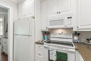 Eine Küche mit weißen Schränken, einem Kühlschrank, einer Mikrowelle und einem Backofen.