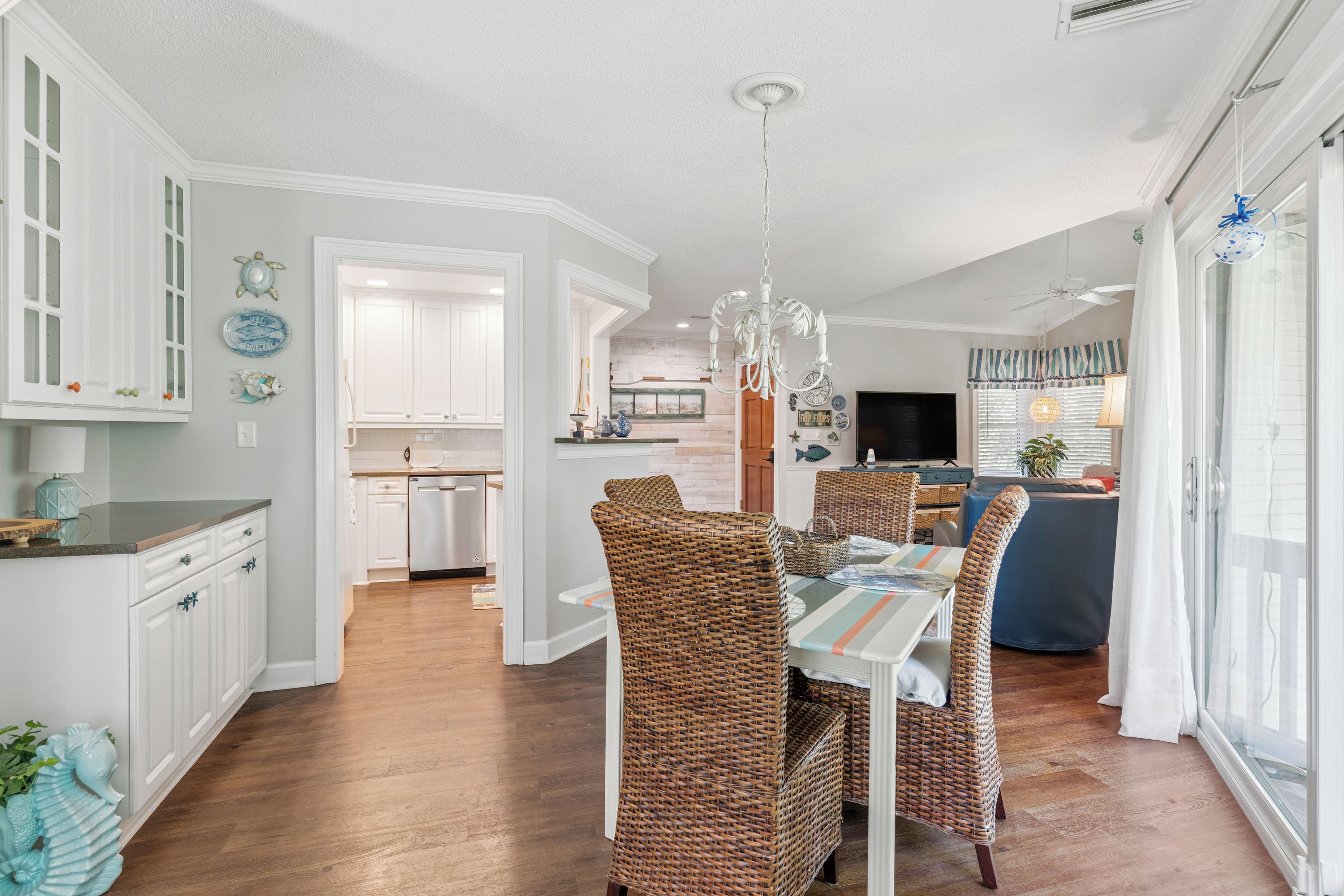 A spacious dining area with a high ceiling and a chandelier, leading to a kitchen and living area.